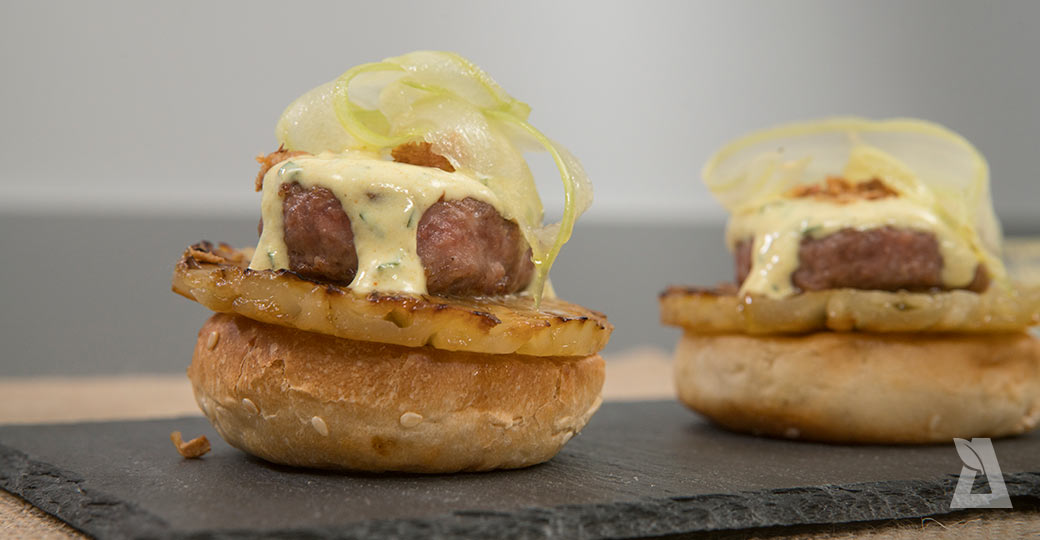 "Montadito" de minihamburguesa con salsa al curri, piña, cebolla crujiente y ensalada de apio