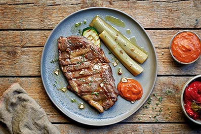 Entrecot a la brasa con calçots confitados, salsa romesco y picada de avellanas