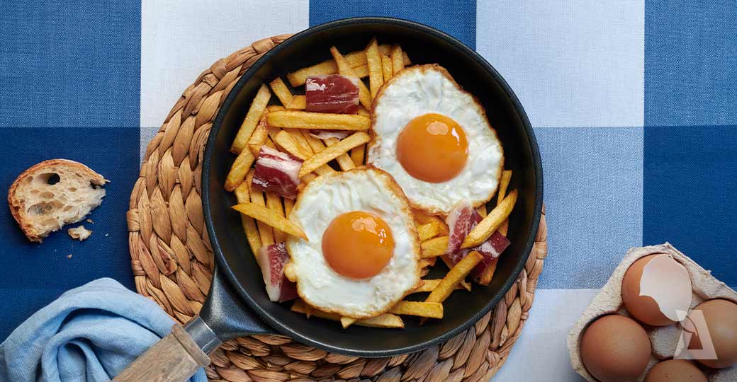 Huevos fritos con patatas fritas y virutas de jamón