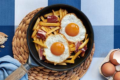 Huevos fritos con patatas fritas y virutas de jamón
