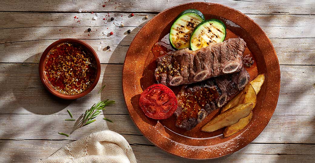 Tiras de churrasco con patatas, verduras a la brasa y salsa chimichurri